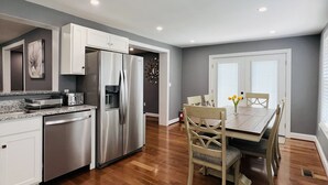 A modern kitchen with stainless steel appliances, a dining area with wooden chairs, and a herringbone-patterned floor. - CHeerful 3-bedroom waterfront home (Riviera Beach)