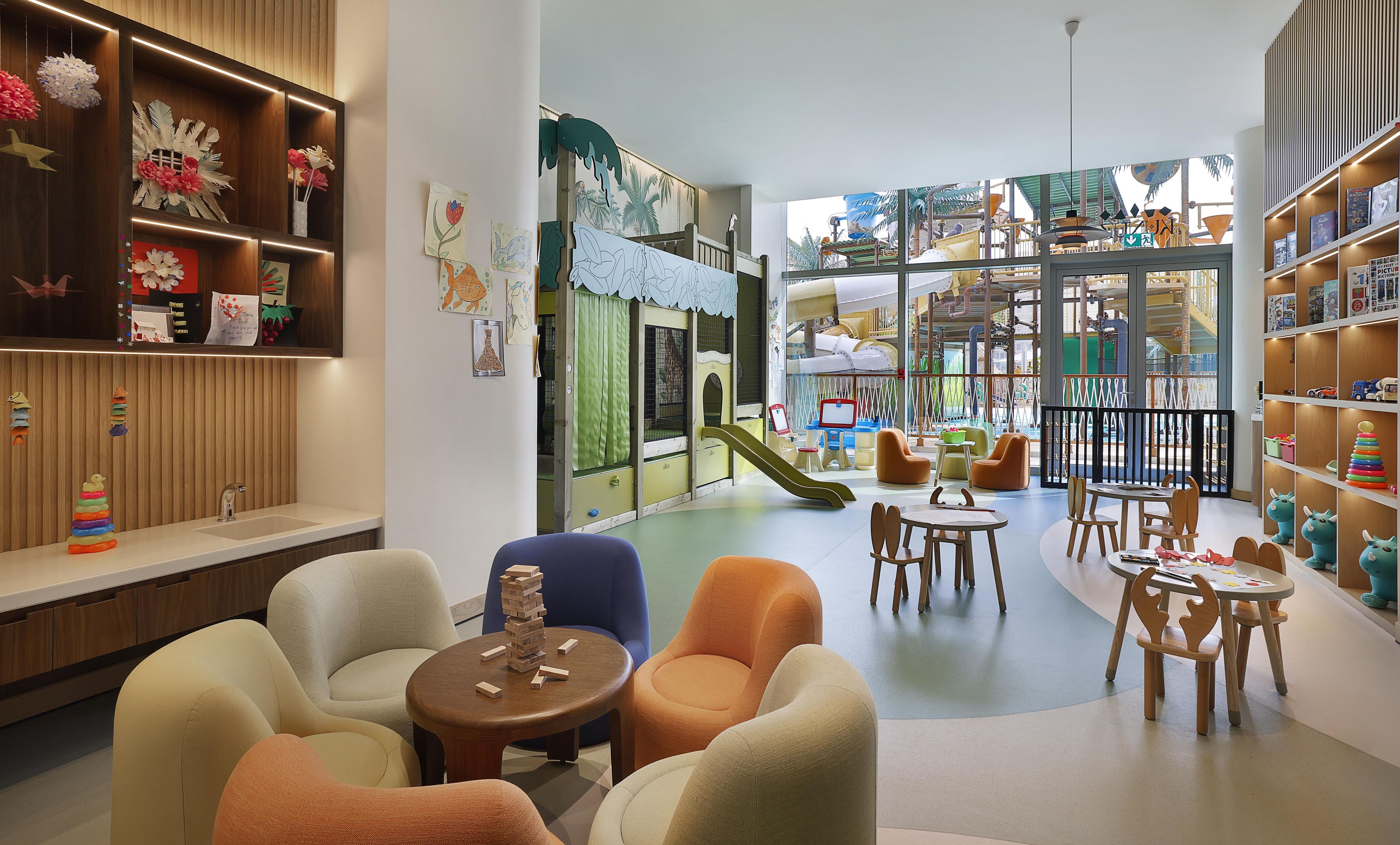 Un espace de jeux pour enfants avec un toboggan, des sièges et une bibliothèque.