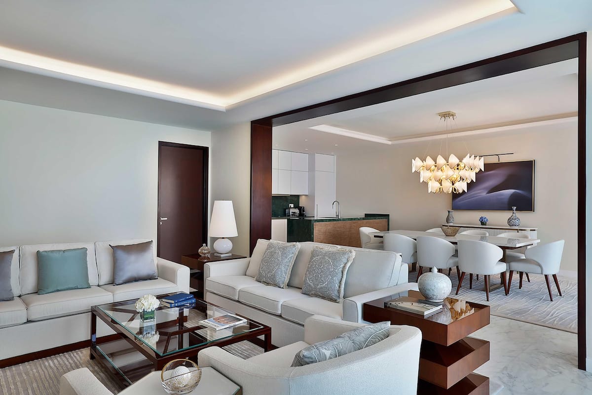 A modern living room with a sofa, coffee table, and dining area with chairs.