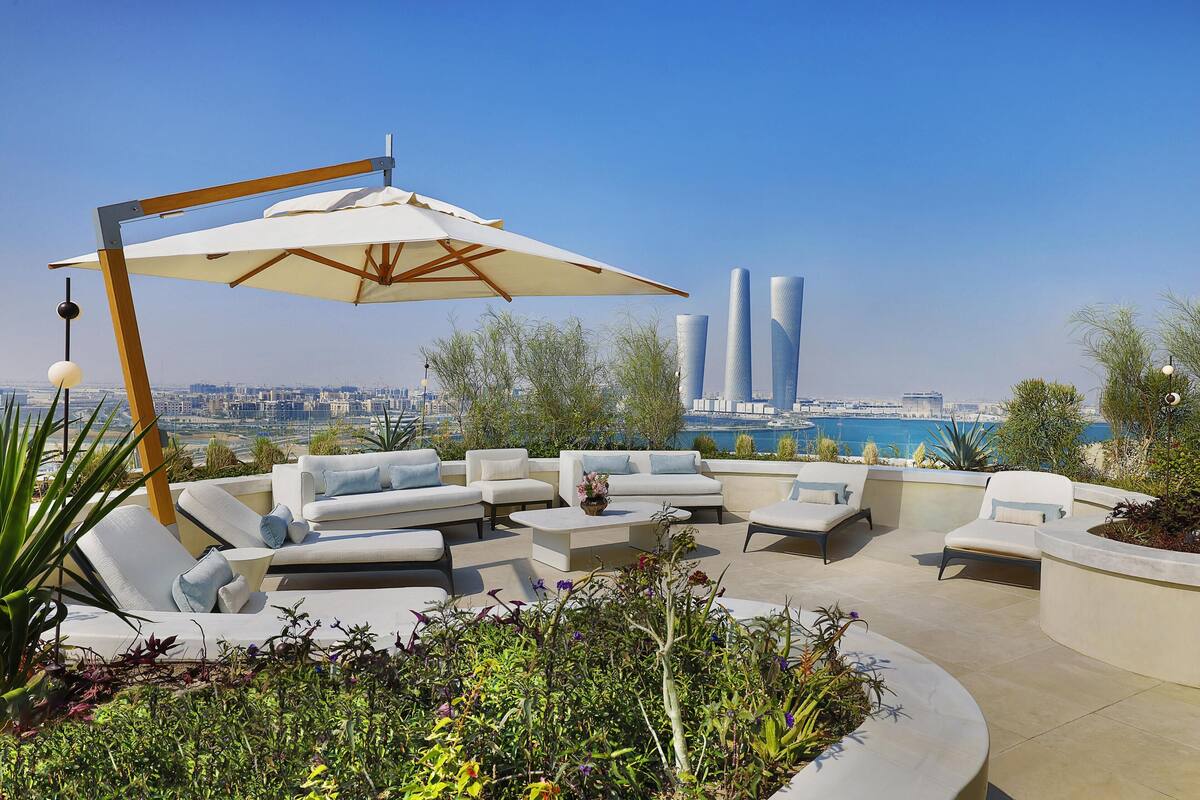 A rooftop terrace with outdoor seating, a large umbrella, and a view of the city skyline.