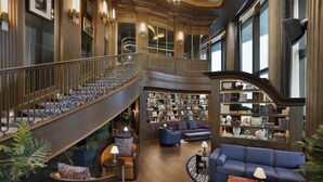 A grand interior with a curved staircase, a library, and seating areas.
