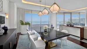 A modern dining area with a glass table, white chairs, and pendant lights.