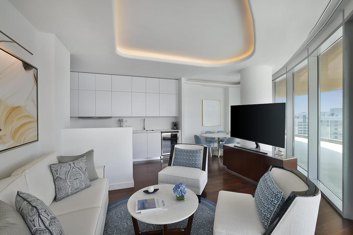 A modern living room with a sofa, armchairs, a coffee table, and a TV.