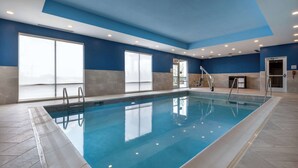 Uma piscina interior com água azul cristalina, rodeada por paredes azulejadas e um teto azul.