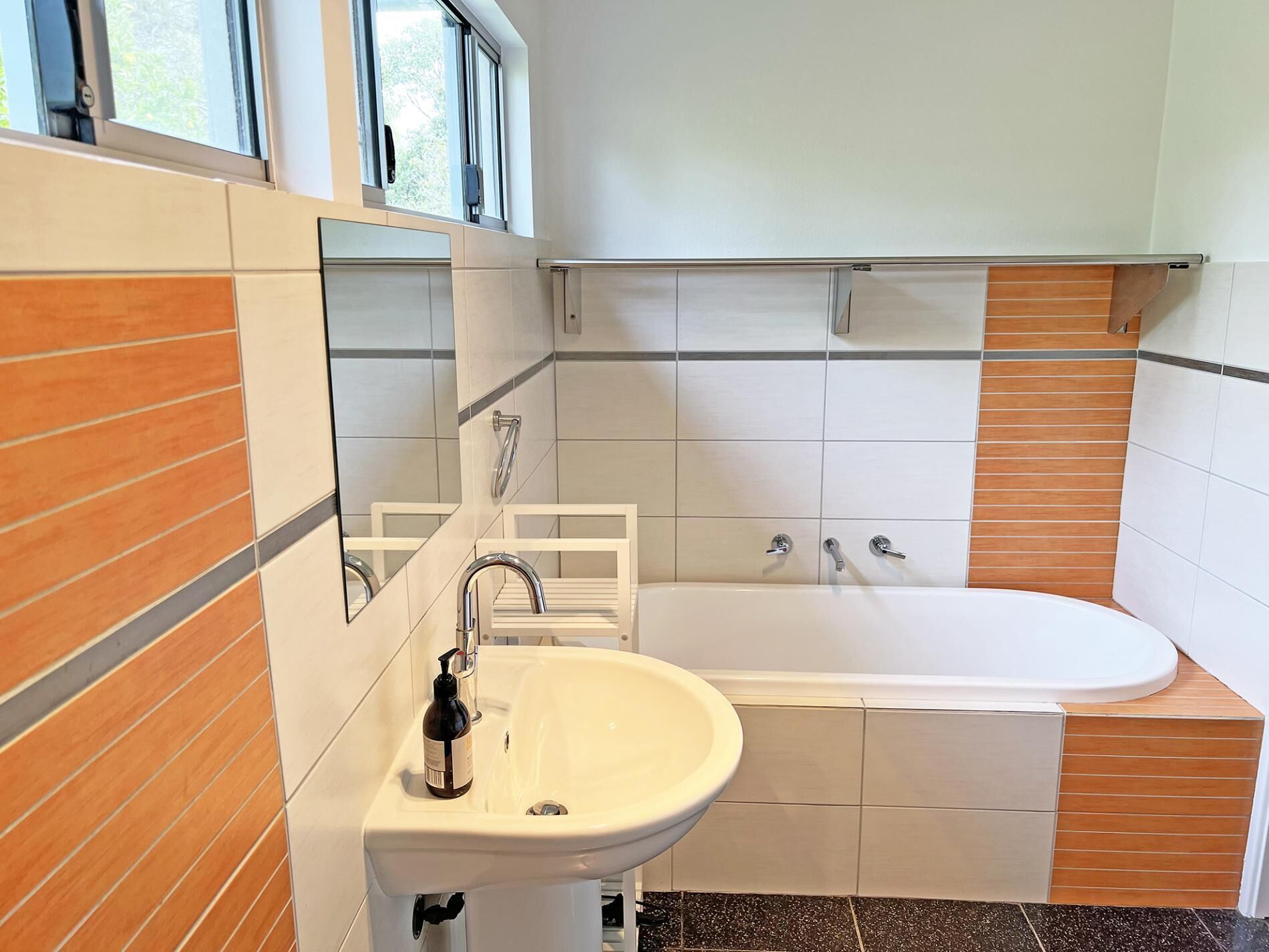 A modern bathroom with a white sink, a mirror, and a bathtub.