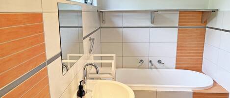 A modern bathroom with a white sink, a mirror, and a bathtub.