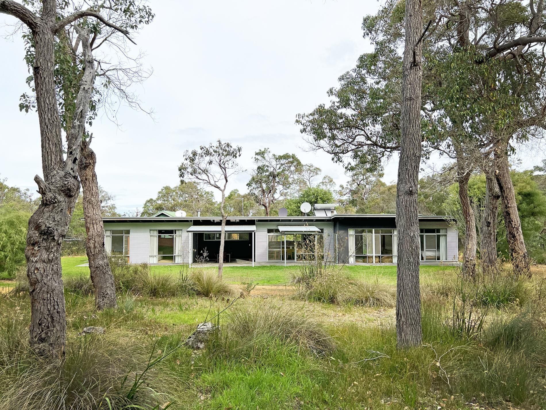 A modern house with a flat roof, large windows, and a covered outdoor area.