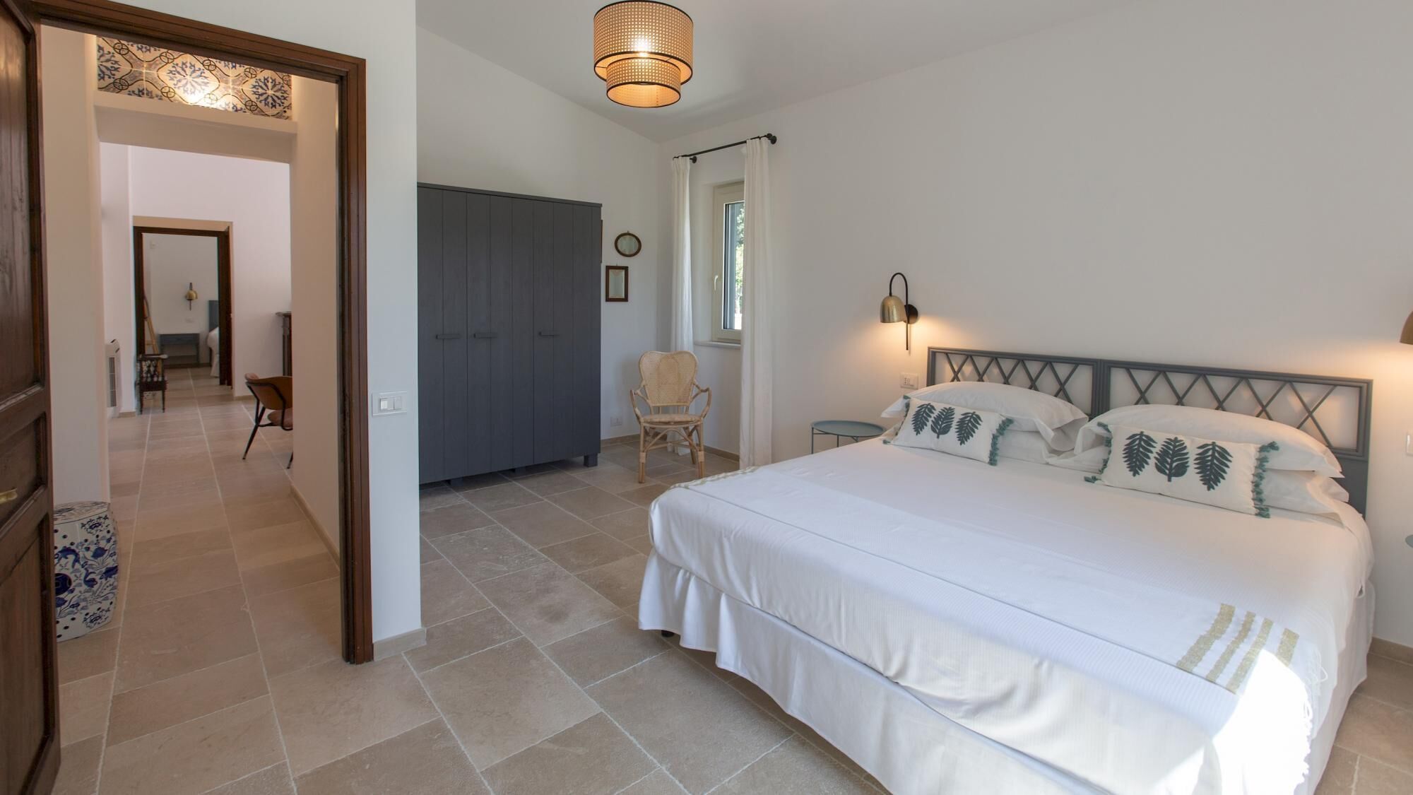 Een slaapkamer met een bed, een stoel, een kast en een raam.