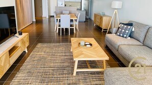 En moderne stue med en sofa, sofabord, TV og et spiseområde med bord og stole.