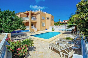 Un bâtiment à deux étages doté d’une piscine, de chaises longues et d’un espace jardin.
