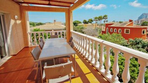 A balcony with a table and chairs, a white balustrade, and a view of buildings and greenery. - Marlene - private pool villa with sea views from the rooftop in Calpe (Calpe)