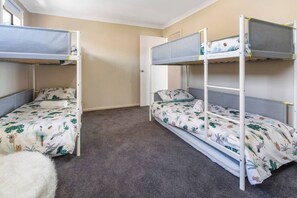 A room with bunk beds, carpeted floor, and a door.