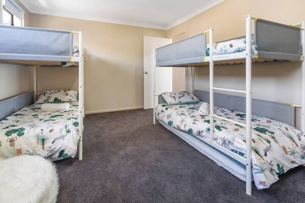 Una habitación con literas, piso alfombrado y una puerta.