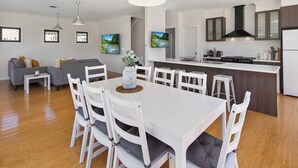 Een moderne keuken met een centraal eiland, witte keukenkastjes en een grijze bank in de woonkamer.