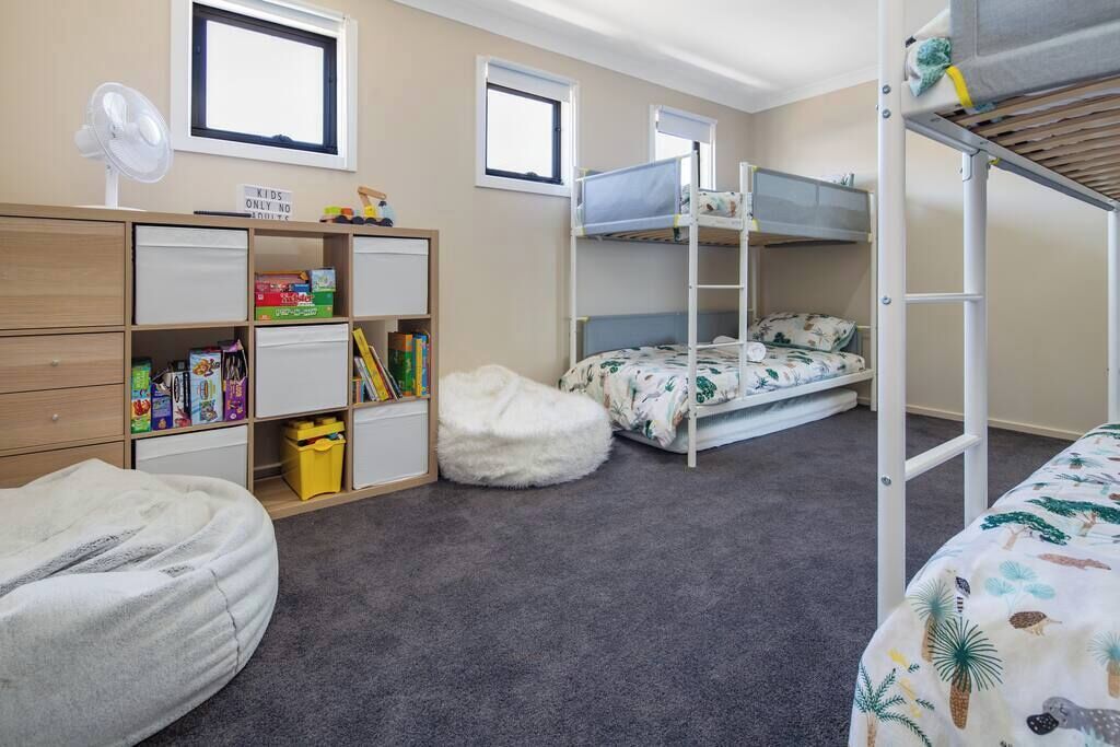 Een kinderkamer met stapelbedden, een bureau met opbergruimte en een relax fauteuil.