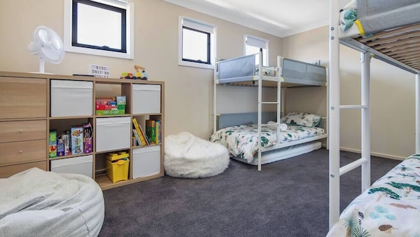 Een kinderkamer met stapelbedden, een bureau met opbergruimte en een relax fauteuil.