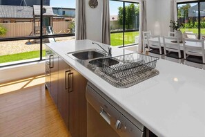 Una cucina moderna con lavastoviglie, doppio lavello e un cesto metallico sul piano di lavoro.