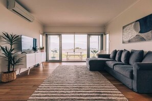 A modern living room with a sofa, a TV, and a large window with a view.