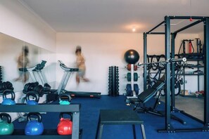 A gym with exercise equipment, including kettlebells, a treadmill, and a squat rack.