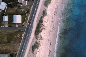 An aerial view of a coastal road with buildings and a beach.