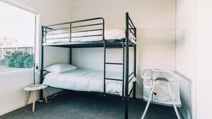 Une chambre avec un lit superposé, une petite table et une chaise blanche.