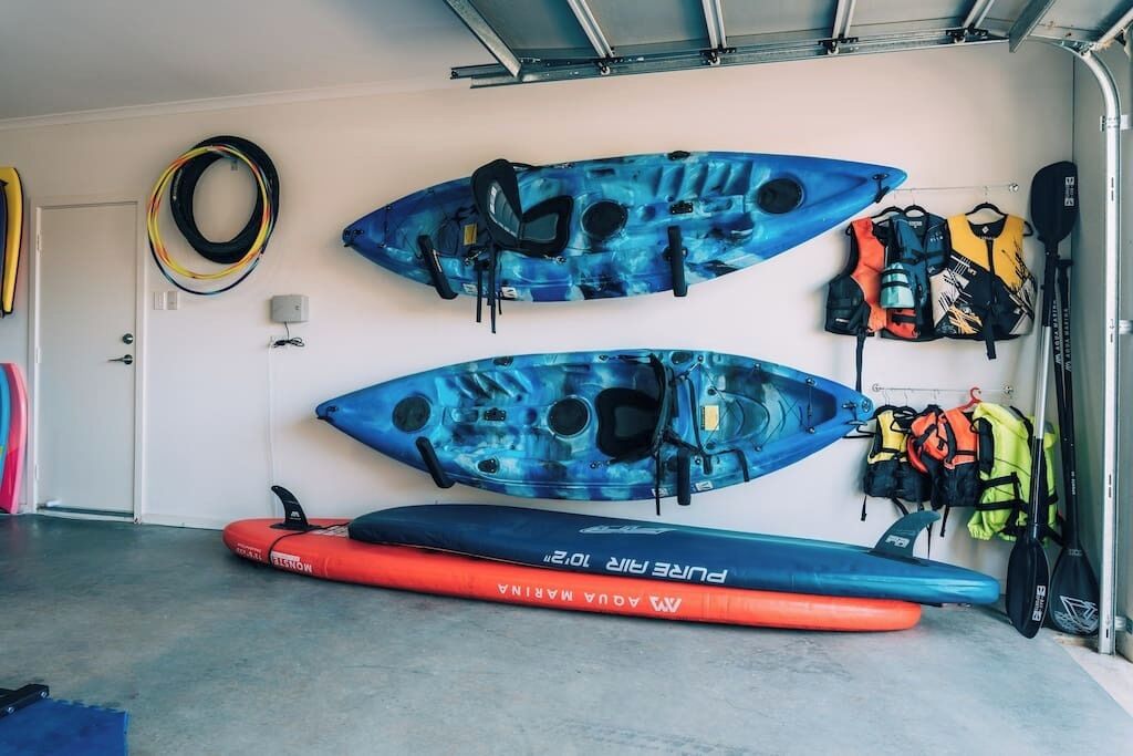 Kayaks and life jackets mounted on a wall in a garage.