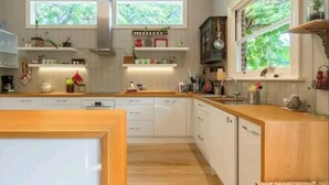 Eine moderne Küche mit weißen Schränken, Holz Arbeitsplatten und integrierten Regalen.