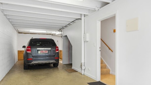 Een voertuig geparkeerd in een garage met een trap naar een hoger gelegen niveau.