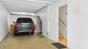 A vehicle parked in a garage with a staircase leading to an upper level.
