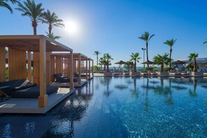 A poolside area with lounge chairs and umbrellas, palm trees, and a clear view of the ocean. - Ammades All Suites Beach Hotel & Spa - Adults Only (Rhodes)