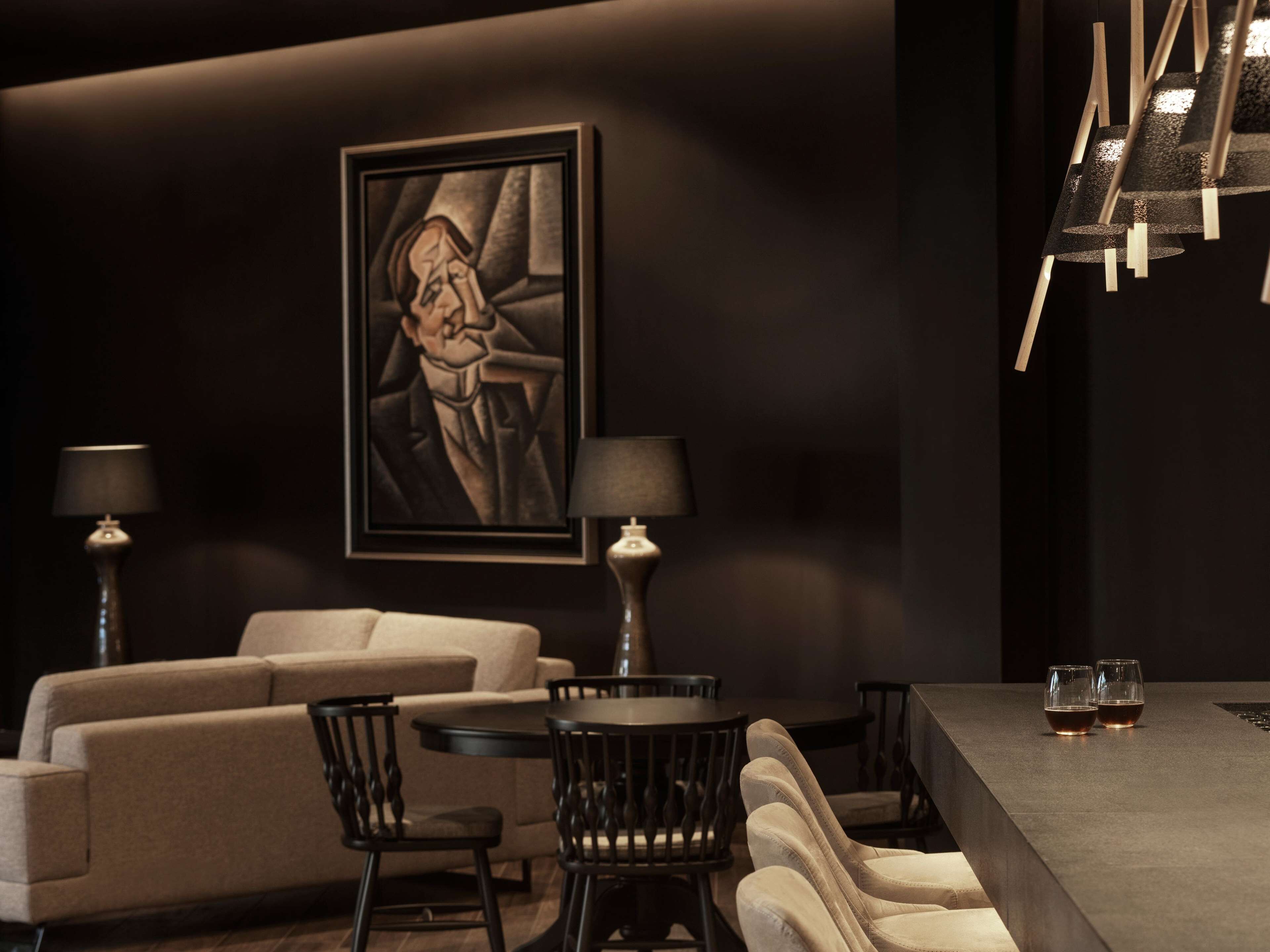 A modern lounge area with a sofa, chairs, a table, and two lamps.