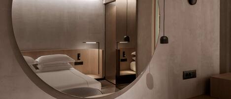 A modern bedroom with a large round mirror, a wooden bed frame, and a bedside table.