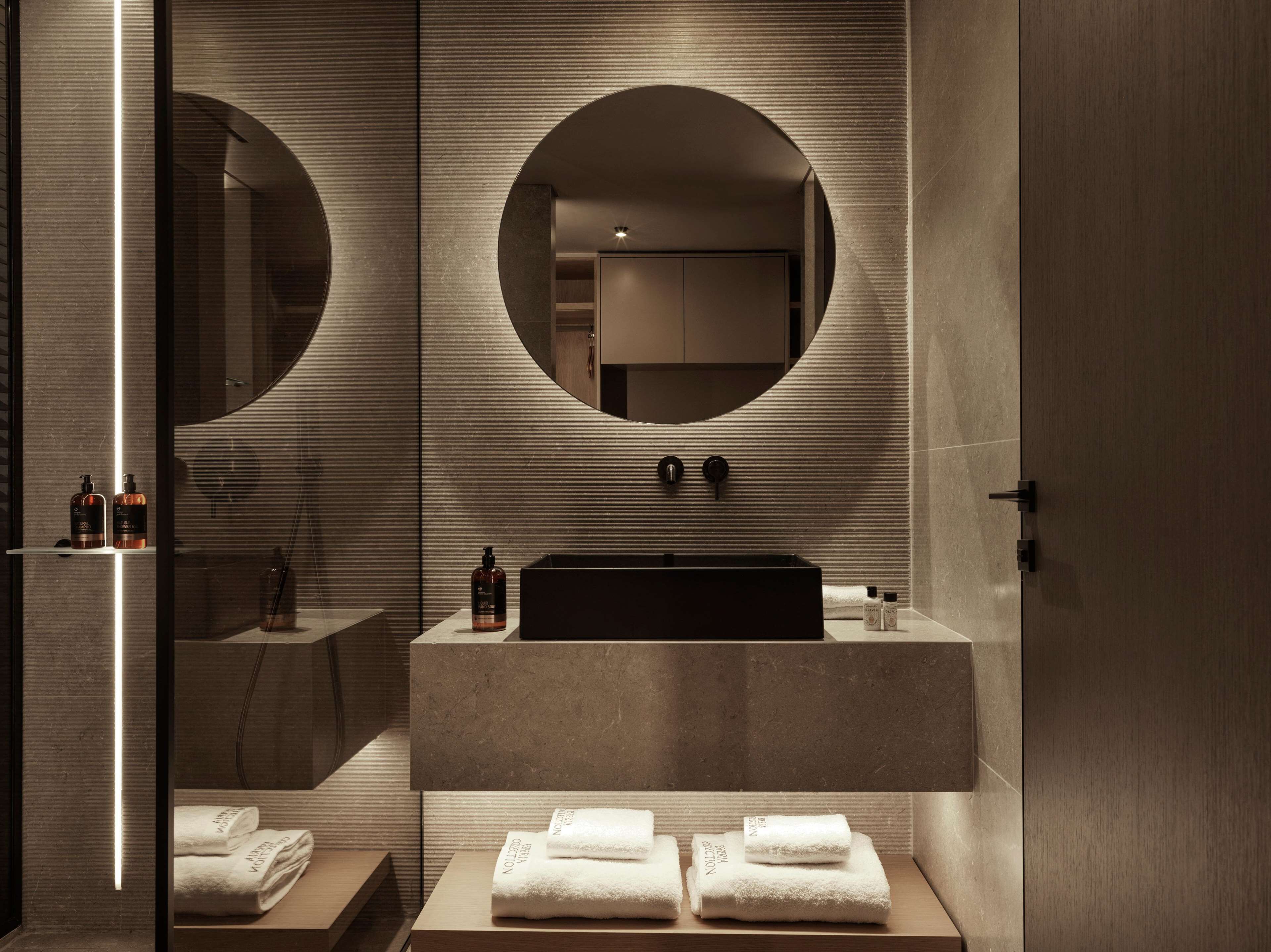 A modern bathroom with a large mirror, a sink, and a towel rack.
