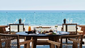 A dining table with chairs and a view of the ocean. - Ammades All Suites Beach Hotel & Spa - Adults Only (Rhodes)