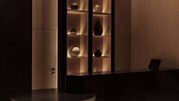 Un área de recepción moderna con un mostrador curvo, estanterías de madera con adornos e iluminación colgante.