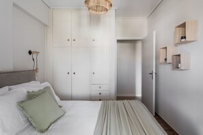 A bedroom with a bed, a wardrobe, a bedside table, and a hanging light fixture. - Signature 2BR Apartment in Marousi (Marousi)