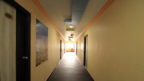 A hallway with doors on both sides, a number sign on one door, and a poster on the wall. - M.G.R. Park Inn (Viluppuram)
