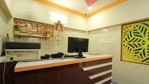 A reception desk with a computer, telephone, and a decorative shelf with flowers. - M.G.R. Park Inn (Viluppuram)