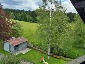 Vista de una casa con un cobertizo pequeño y un árbol en el jardín.