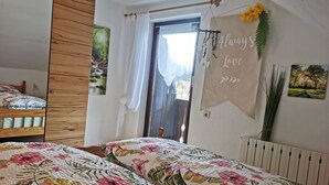 Une chambre avec deux lits, une armoire en bois, une fenêtre avec des rideaux et des éléments de décoration murale, notamment un panneau portant l’inscription « Toujours aimer » et une image d’arbres.