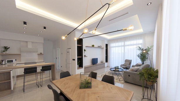 A modern kitchen with a wooden dining table, black chairs, and a built-in oven.