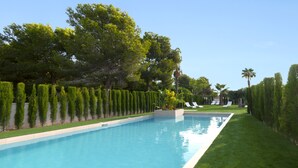 A rectangular swimming pool with a clear blue water surface, surrounded by neatly trimmed hedges and a well-maintained lawn.