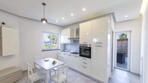 Una cucina moderna con mobili bianchi, un fornello a gas e un'area pranzo con tavolo e sedie.