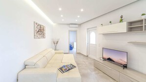 Un soggiorno moderno con un divano beige, una TV a schermo piatto e un design minimalista.
