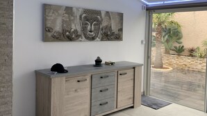 Un intérieur moderne avec un meuble en bois, un tableau représentant un Bouddha et un plafond doté de lumières LED bleues.