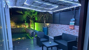 Un espace patio avec des sièges extérieurs, une piscine et un mur de briques orné de panneaux indicateurs.