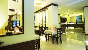 A hotel lobby with a reception desk, several dining tables, and a decorative wall piece. - P.S. Hotel -SHA Plus (Patong)