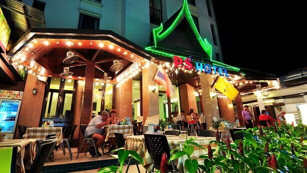 A hotel with outdoor seating and a green neon sign. - P.S. Hotel -SHA Plus (Patong)