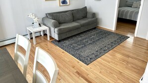 A modern living room with a grey sofa, a small white table, and a patterned rug.