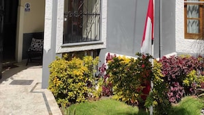 Un edificio con un letrero que dice "Runway Hotel" y un asta con una bandera. Se observan tres ventanas arqueadas y una puerta con un portón metálico.